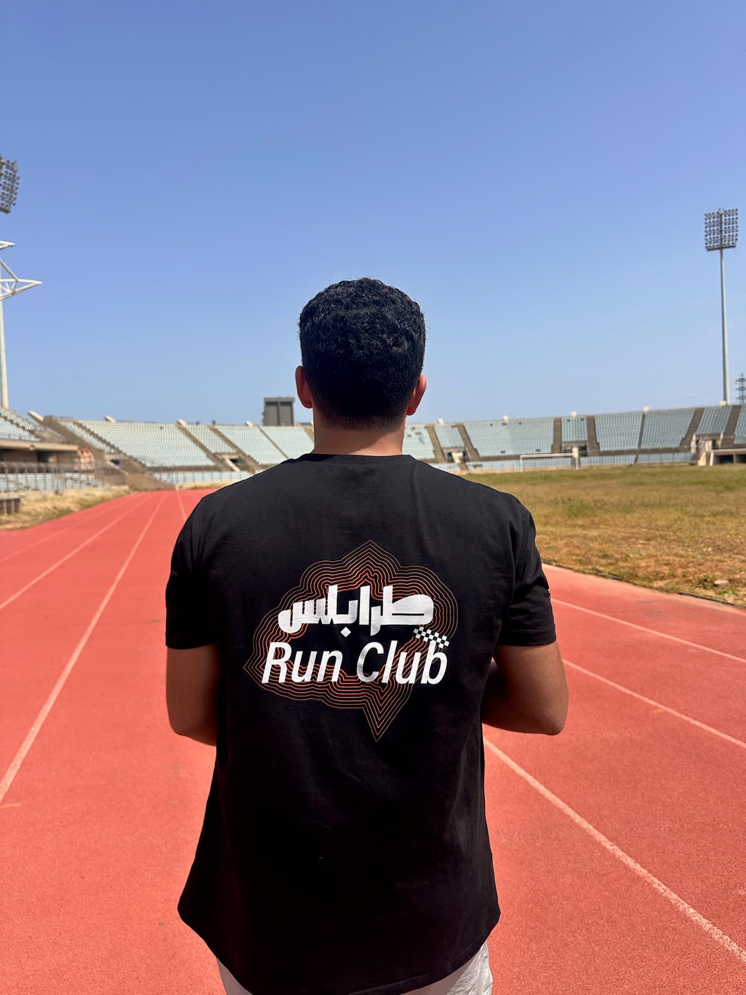 Runner showing off the TRC Arabic shirt on the stadium track
